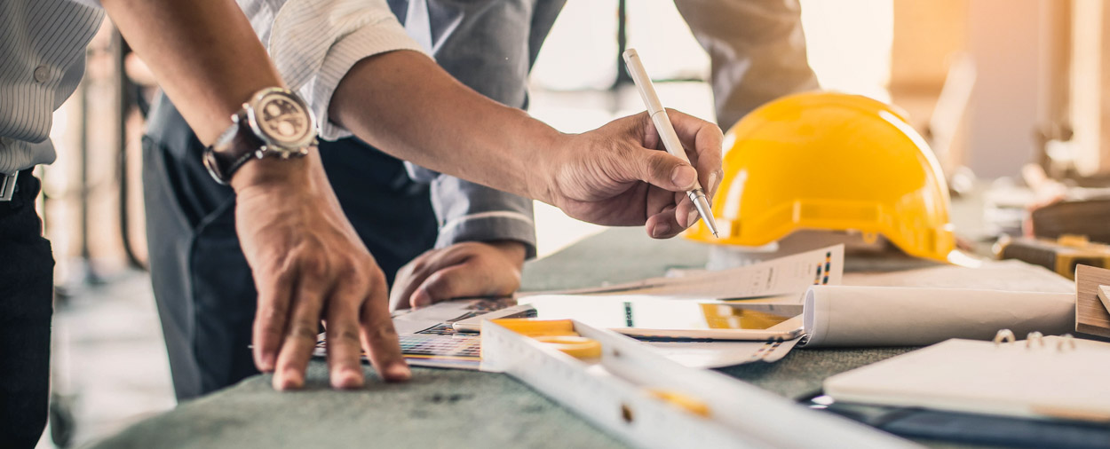 Profesionales de la construcción colaborando en planos de obra, representando las oportunidades de empleo y alianza con contratistas de GQM Inc. en toda Florida.